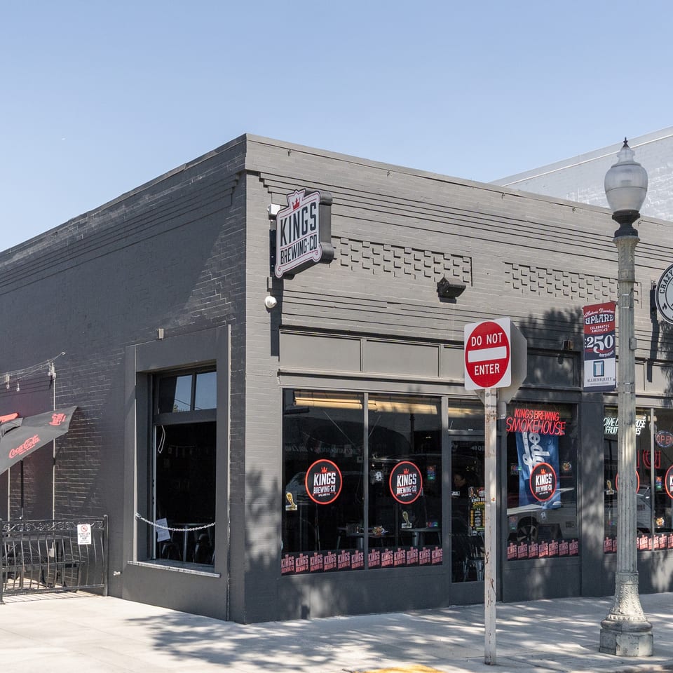 Exterior of Kings Brewing Co. and Crazy Gringo BBQ, a gray brick building with outdoor patio seating.
