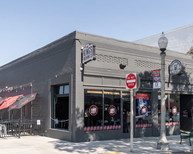 Exterior of Kings Brewing Co. and Crazy Gringo BBQ, a gray brick building with outdoor patio seating.